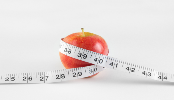 Apple wrapped in measuring tape representing healthy weight loss